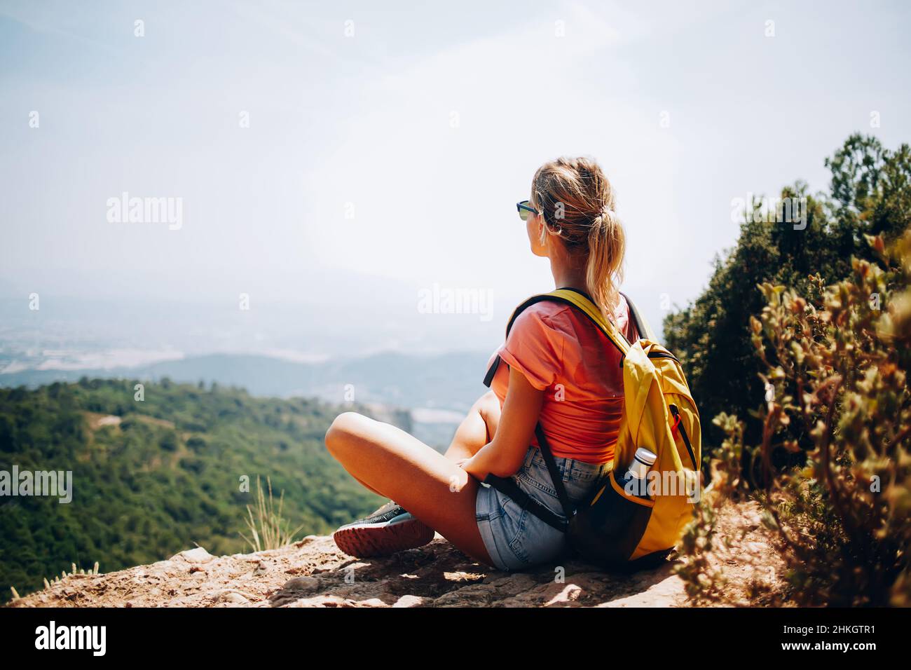 Femme voyageur assise sur une colline avec sac à dos Banque D'Images