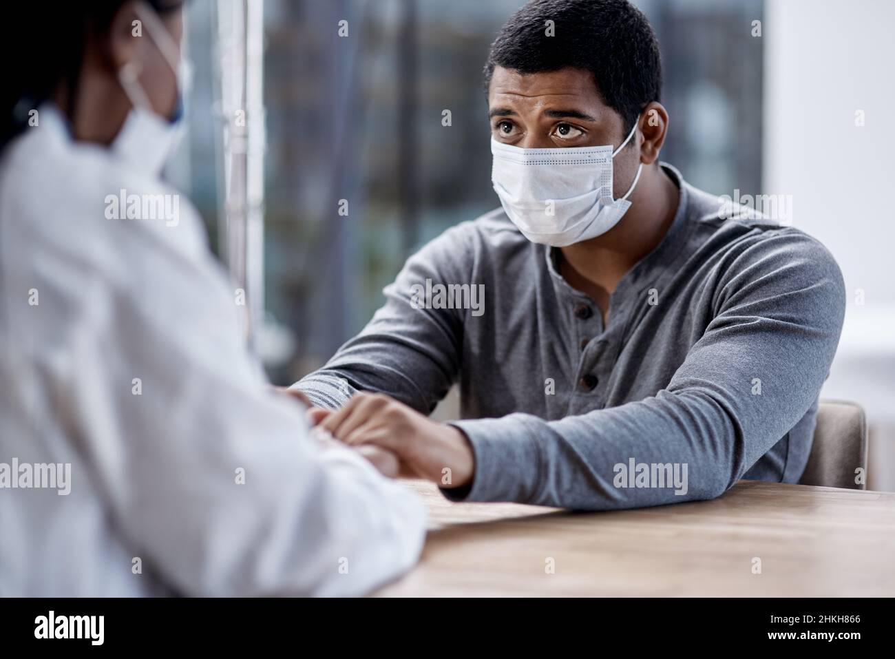 Comment mauvais est-il, docteur.Prise de vue d'un jeune homme tenant les mains d'un médecin au cours d'une consultation. Banque D'Images
