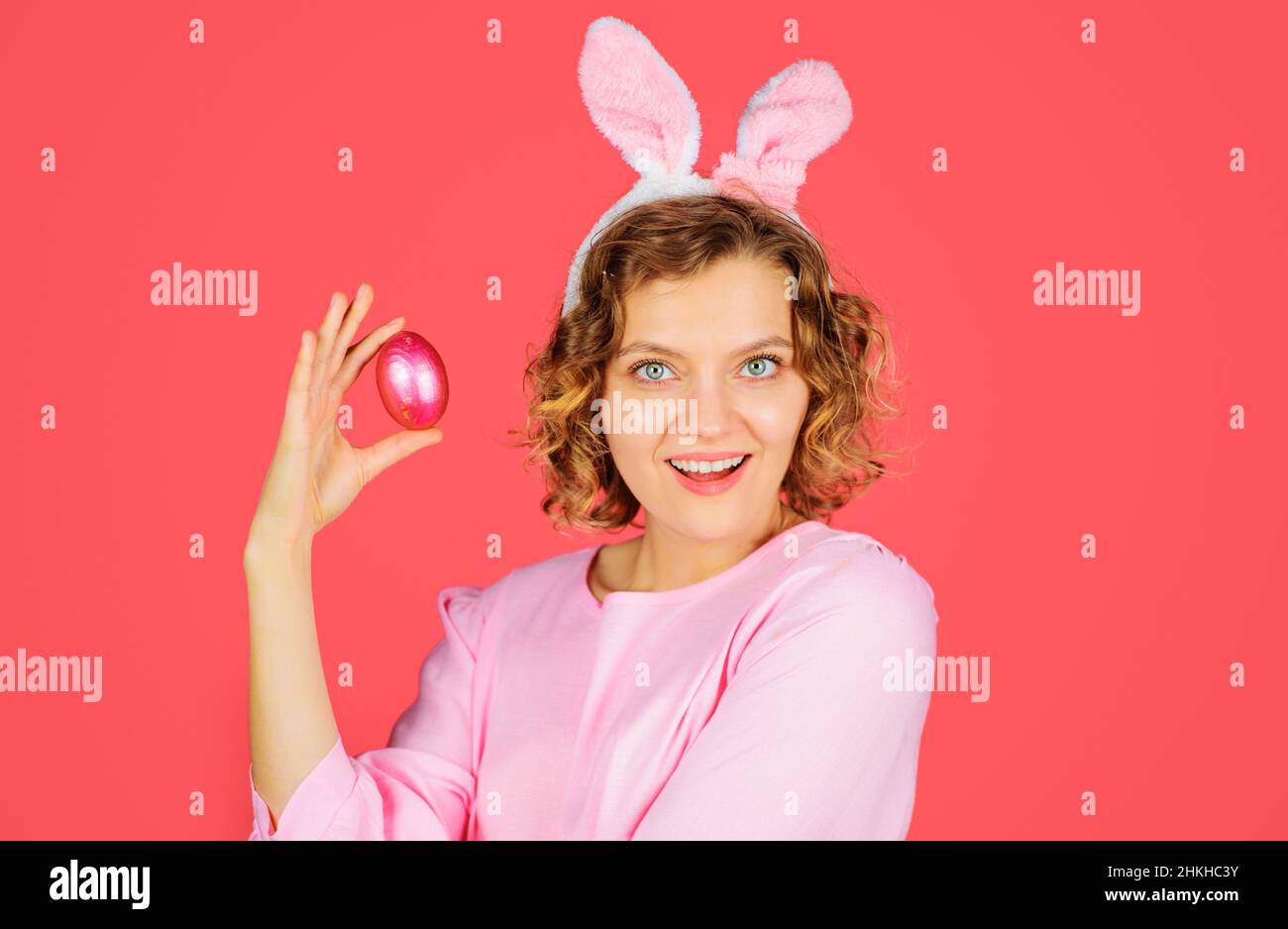 Chasse aux œufs.Joyeuses Pâques.Femme souriante dans les oreilles de lapin avec un œuf rose.Fille de lapin.Vacances de printemps Banque D'Images