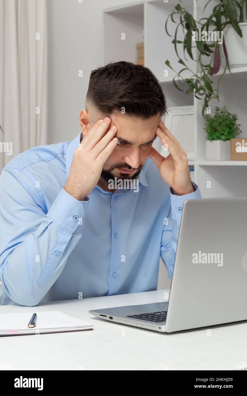 Douleur à la tête d'un homme d'affaires fatigué travaillant sur un ordinateur portable. Banque D'Images