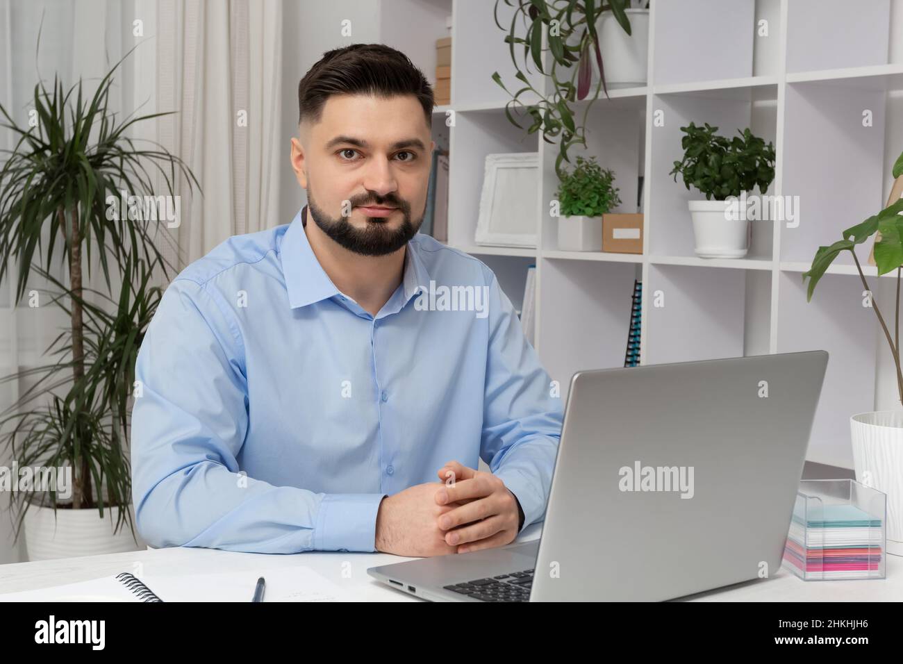 Portrait d'un homme d'affaires assis sur son lieu de travail avec un ordinateur portable. Banque D'Images