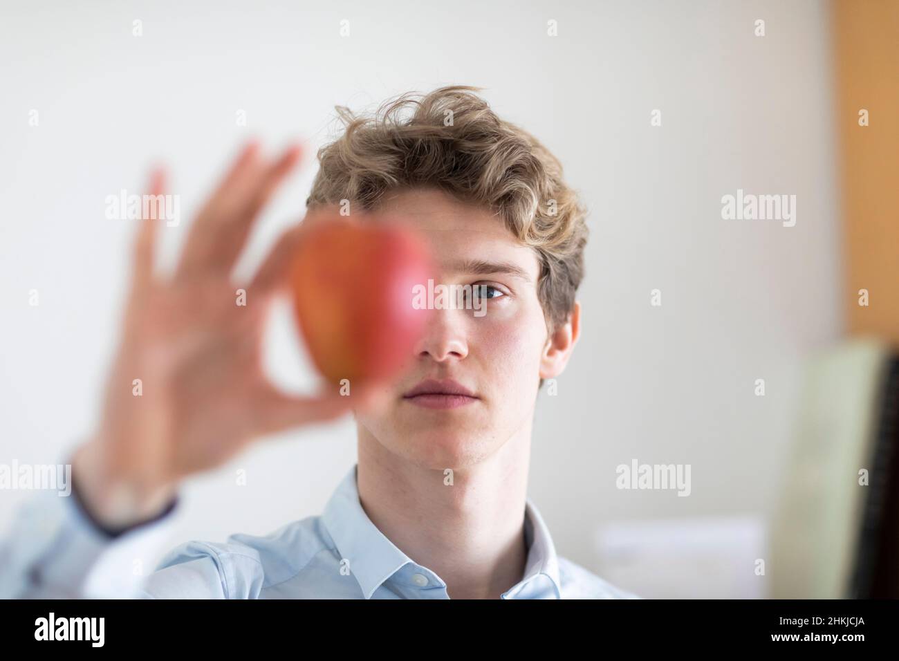 jeune homme aux cheveux blonds et une pomme dans la main Banque D'Images