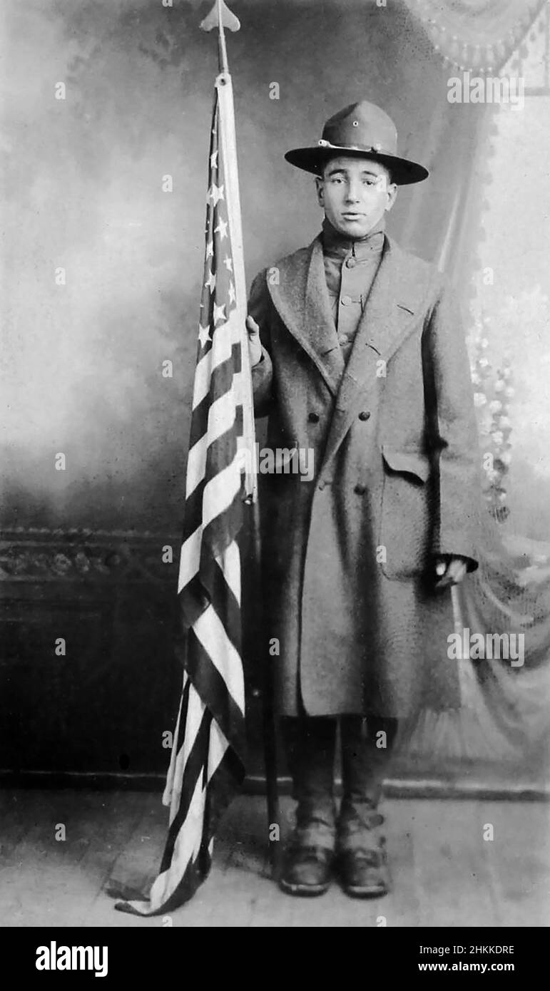 Le soldat de la guerre mondiale 1 pose avec un drapeau américain dans un portrait officiel, ca. 1917. Banque D'Images