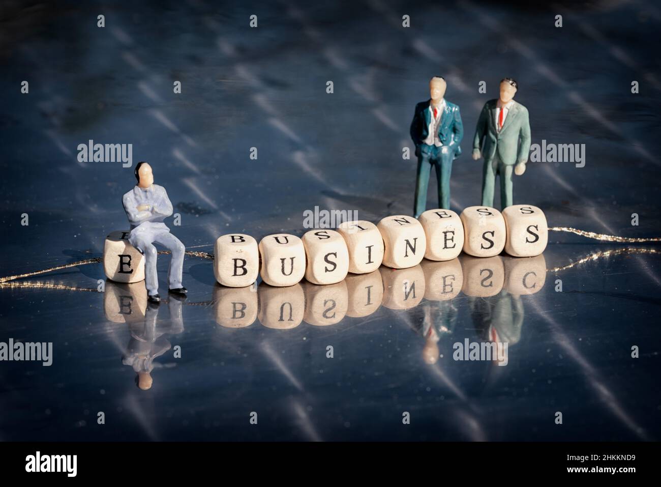 Modèle miniature d'hommes d'affaires et cubes en bois avec inscription d'affaires sur un fil sur une table réfléchissante.Le concept d'entreprise en ligne. Banque D'Images