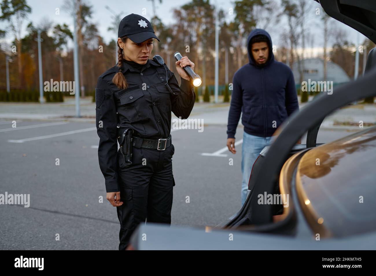 Femme policier inspectant la voiture avec une lampe de poche Banque D'Images