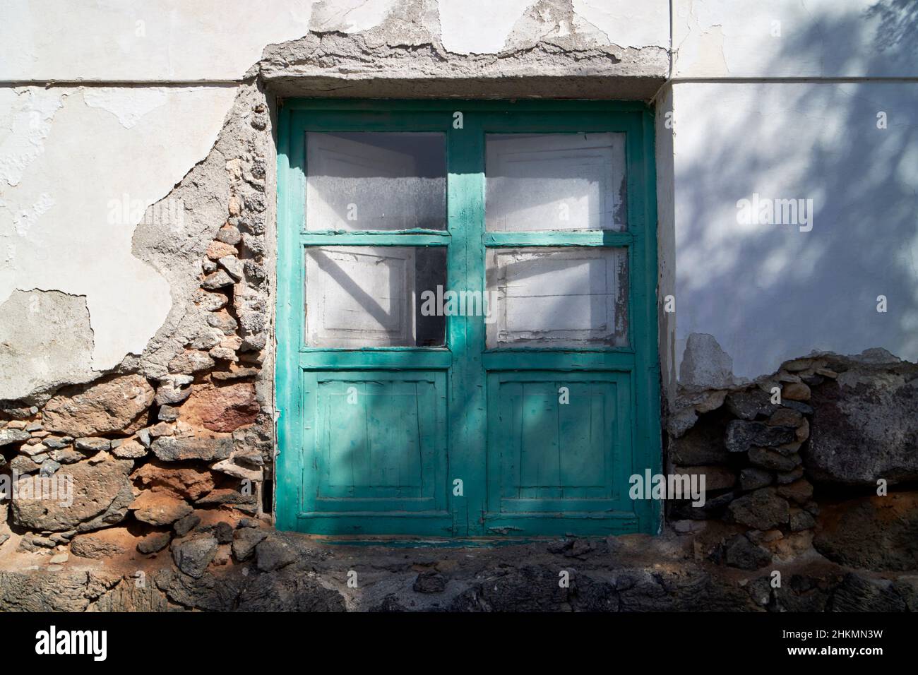 Fenêtres en bois peintes de couleur verte avec volets intérieurs typique de construction canarian maison avec rendu cassé pour révéler la construction de roche volcanique Teguis Banque D'Images