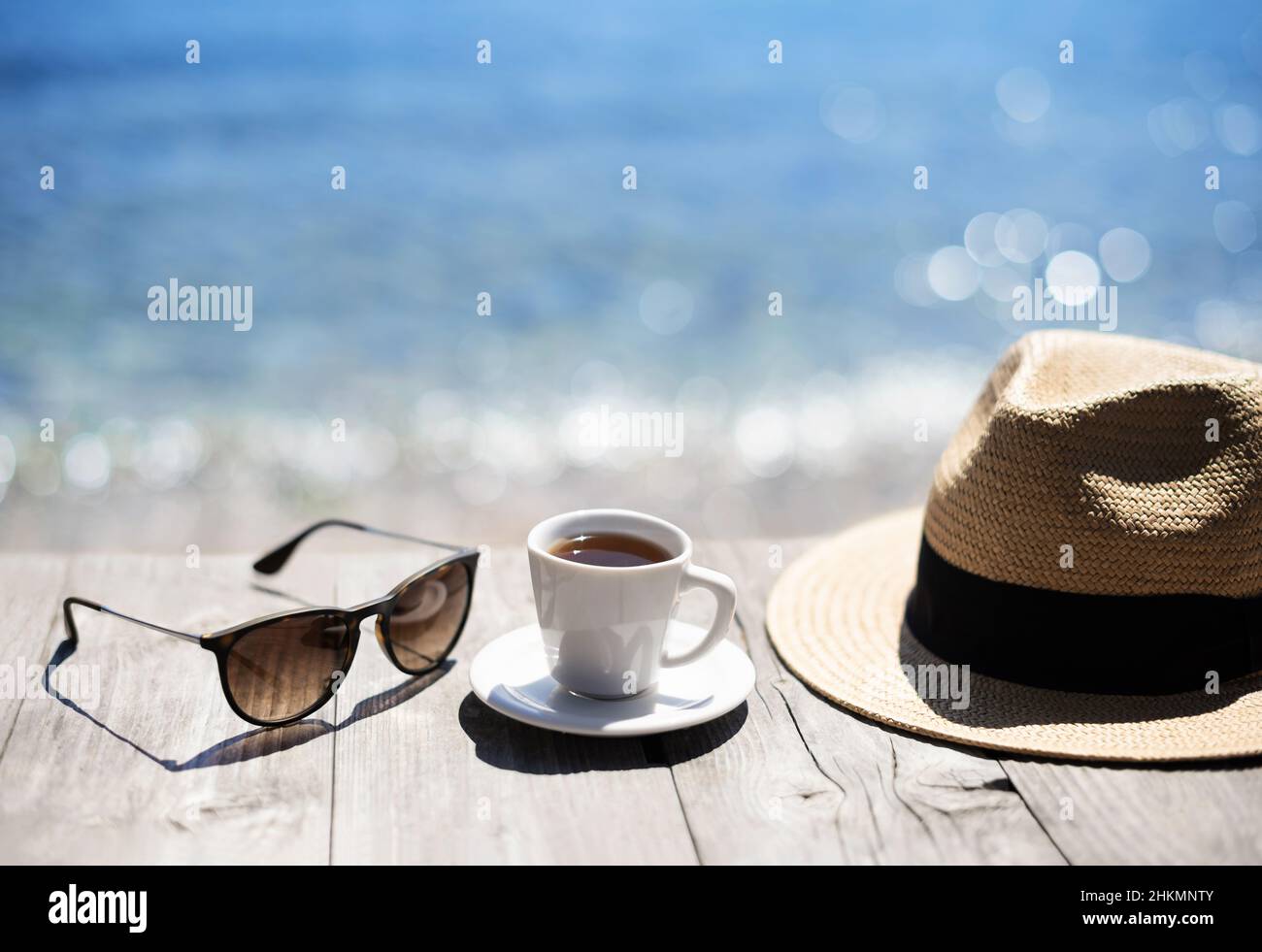 Tasse à café, chapeau de paille et lunettes de soleil sur une table en bois sur fond de mer. Vacances, amusement d'été, profiter de la vie concept Banque D'Images