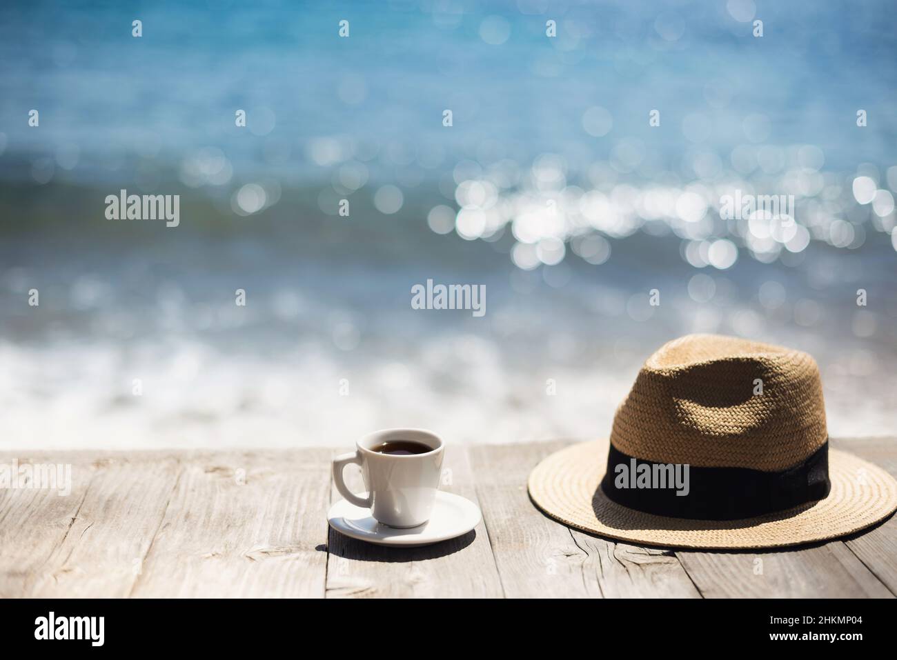 Tasse à café, chapeau de paille et lunettes de soleil sur une table en bois sur fond de mer. Vacances, amusement d'été, profiter de la vie concept Banque D'Images
