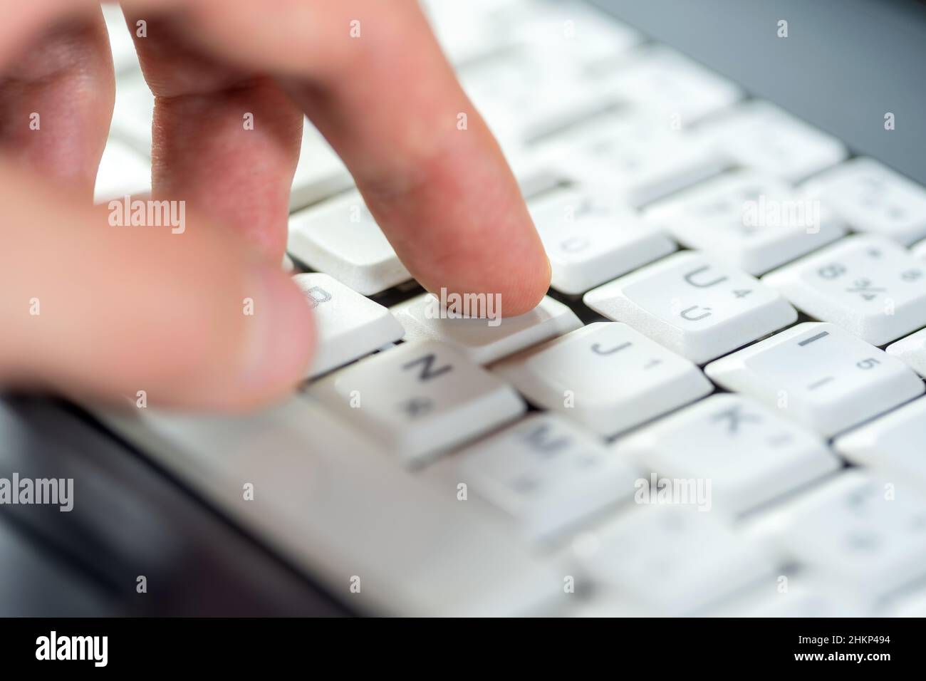 Doigt appuyant sur une seule touche d'un clavier blanc d'ordinateur portable, dof peu profond, macro d'objet, détail, gros plan extrême.Utilisation d'un ordinateur, expérience utilisateur, Inte Banque D'Images
