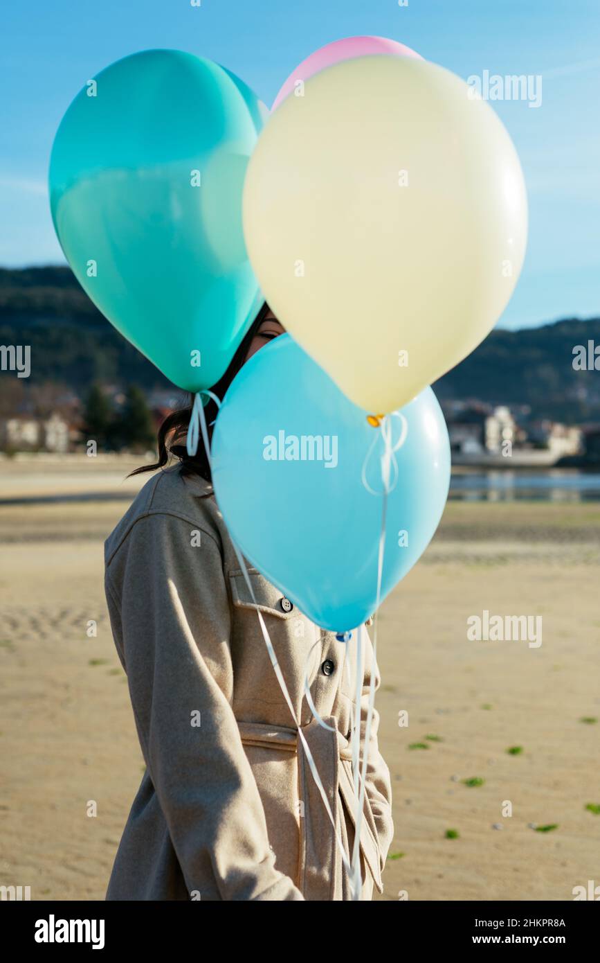 Jeune femme couvrant son visage avec des ballons Banque D'Images