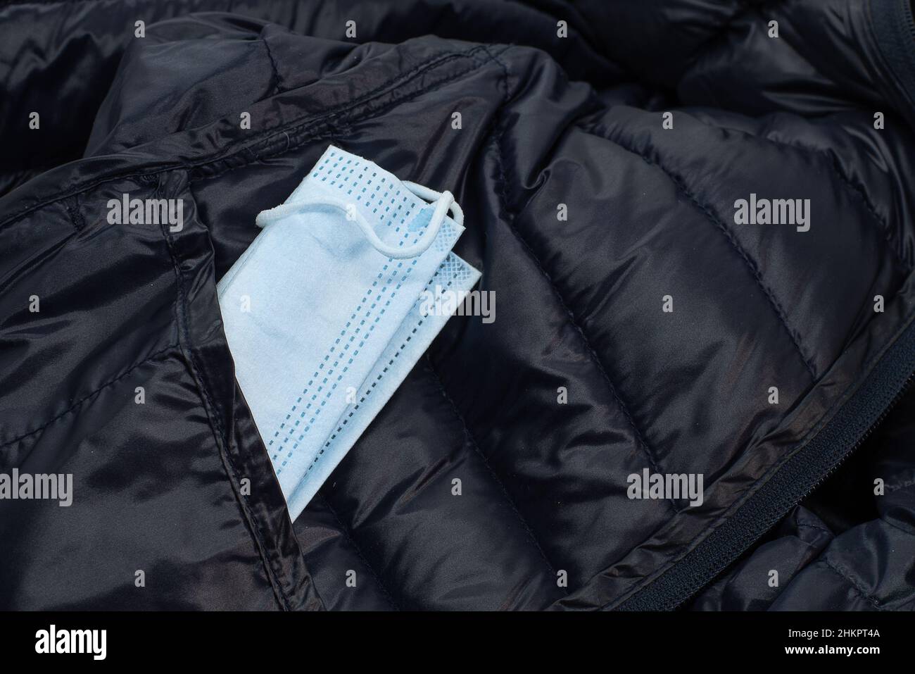 Masque facial bleu sortant de la poche sur une veste bleue en duvet, Frederikssssund, Danemark, 4 février 2022 Banque D'Images