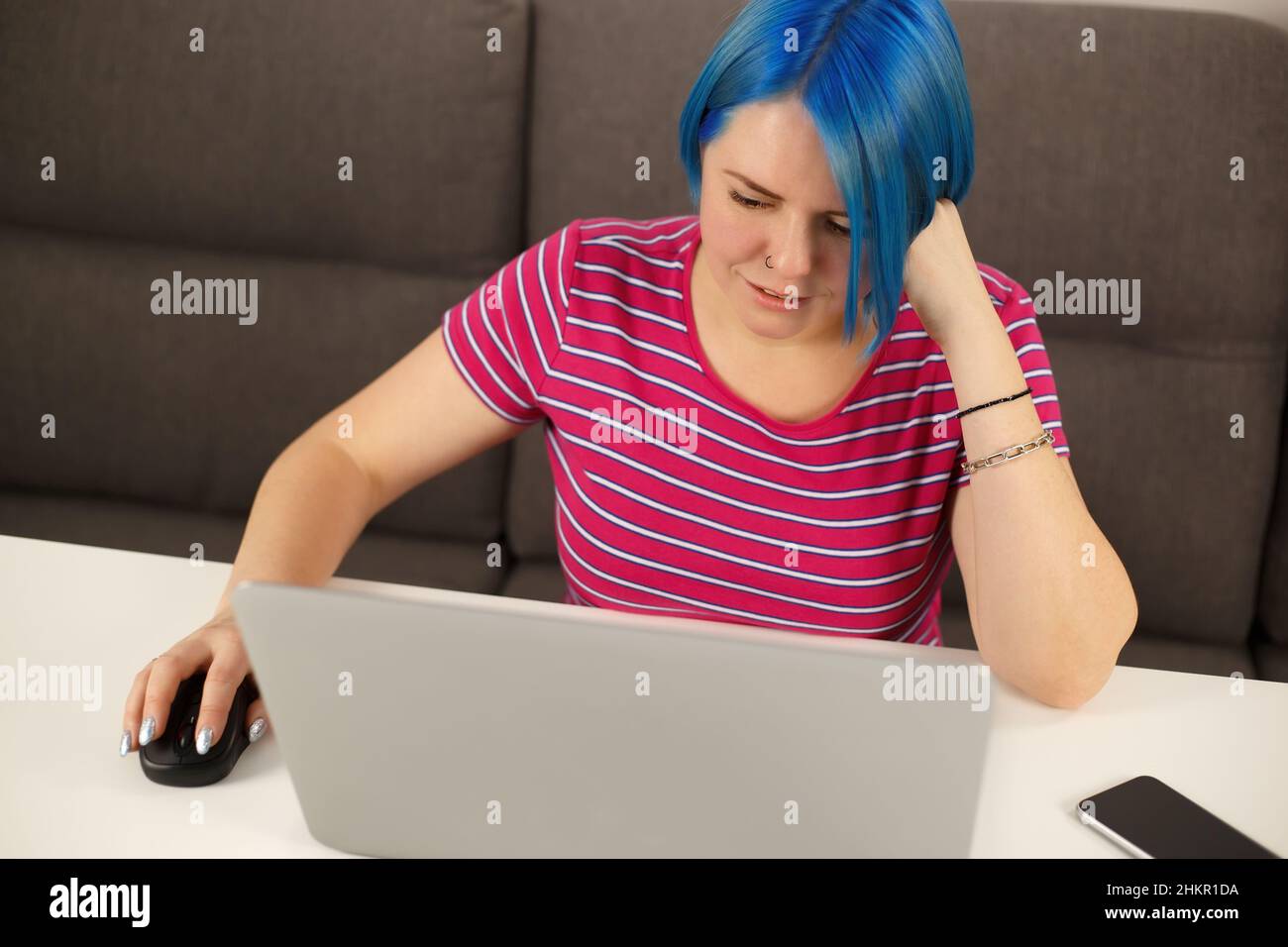 Jeune femme blanche aux cheveux bleus travaillant sur un ordinateur portable.Mignonne caucasienne avec la coiffure de Bob de couleur en utilisant un ordinateur portable moderne pour le travail en ligne Banque D'Images