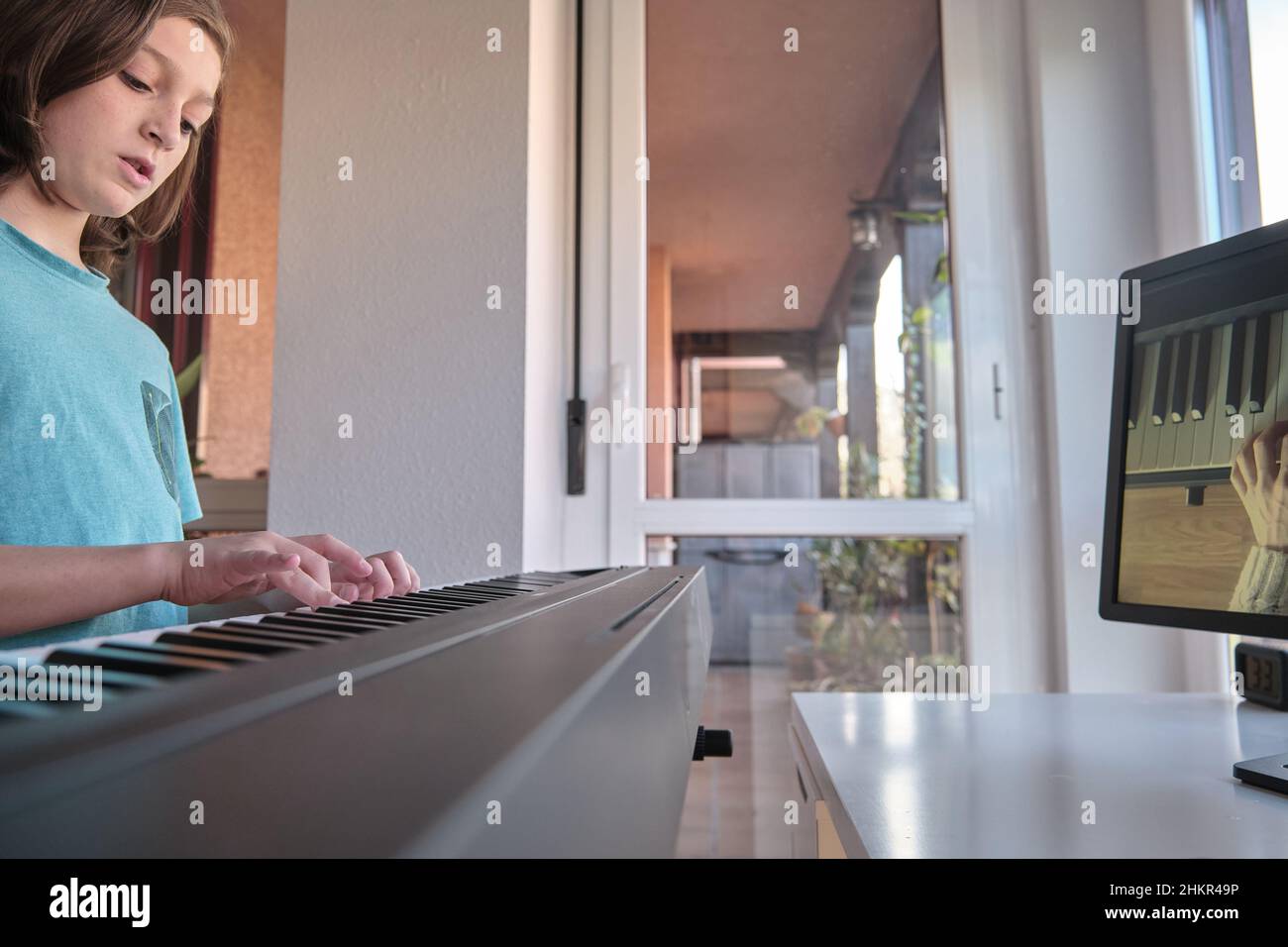Caucasien Boy apprendre à jouer du piano avec des leçons de vidéo.Concept d'apprentissage virtuel Banque D'Images