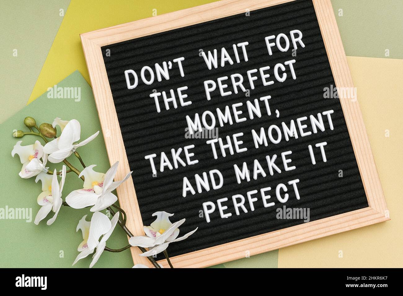 N'attendez pas le moment parfait, prenez le moment et rendez-le parfait.Citation motivationnelle sur le cadre du tableau de lettres et orchidée de fleur sur fond vert Banque D'Images