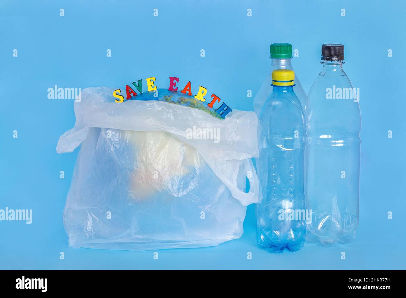 Inscription SAUVE TERRE, bouteilles en plastique, terre abstraite dans sac en polyéthylène, fond bleu.Concept écologie problème de pollution de l'environnement plan Banque D'Images