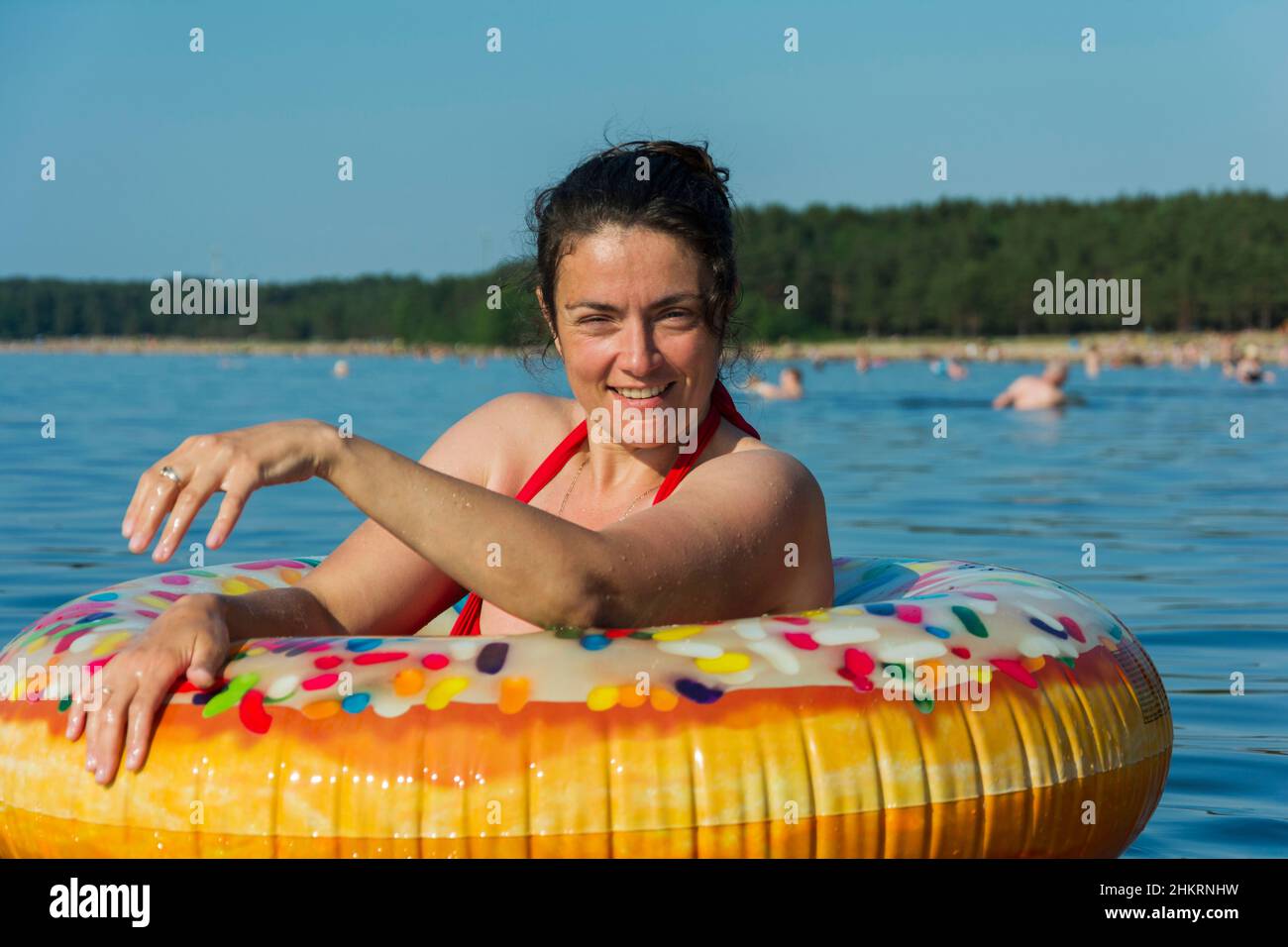 Mignonne jeune femme avec le cercle gonflable coloré nage dans l'eau bleue de la mer sur une chaude journée ensoleillée, donut pour nager, plage d'été vaca Banque D'Images