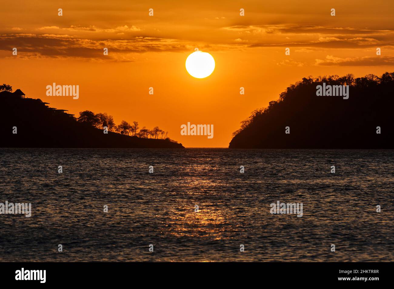 Une belle image du soleil couchant et ciel orange brumeux entre deux masses au large de la côte du Costa Rica. Banque D'Images