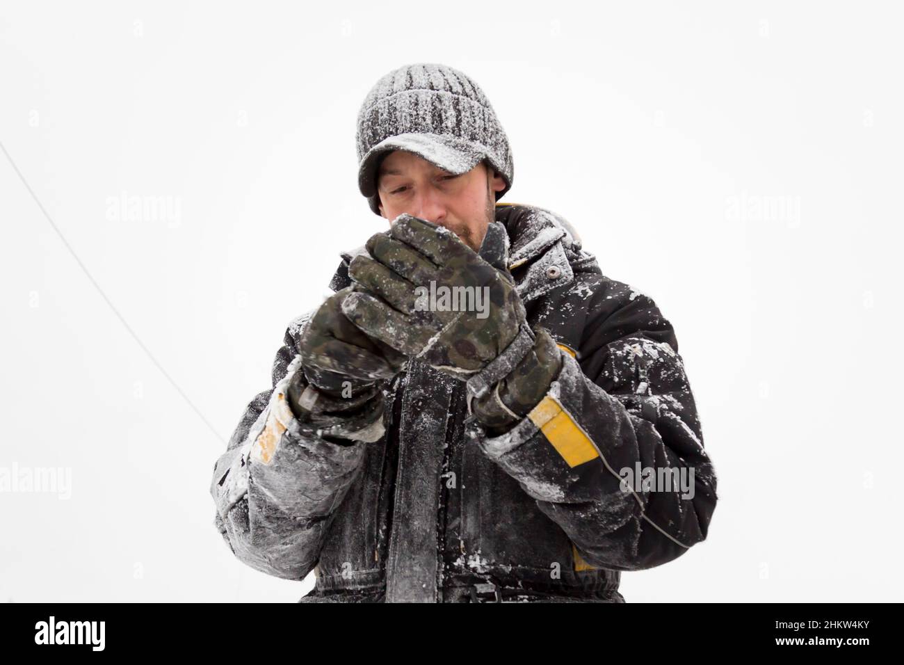 Le monteur dans une veste et une casquette noire avec visière met des gants Banque D'Images