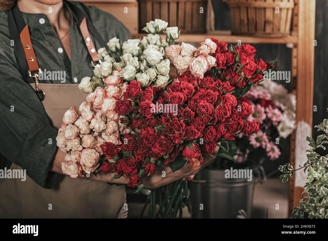 Femmes fleuristes mains tenant un grand bouquet de roses.Lieu de travail du fleuriste.Concept de petite entreprise.Boutique de fleurs et d'accessoires.Gros plan Banque D'Images