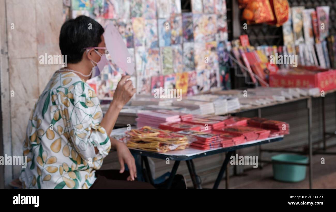 Dame portant des lunettes et un masque vendant des enveloppes rouges du nouvel an chinois pour les cadeaux Chinatown Bangkok Thaïlande Banque D'Images