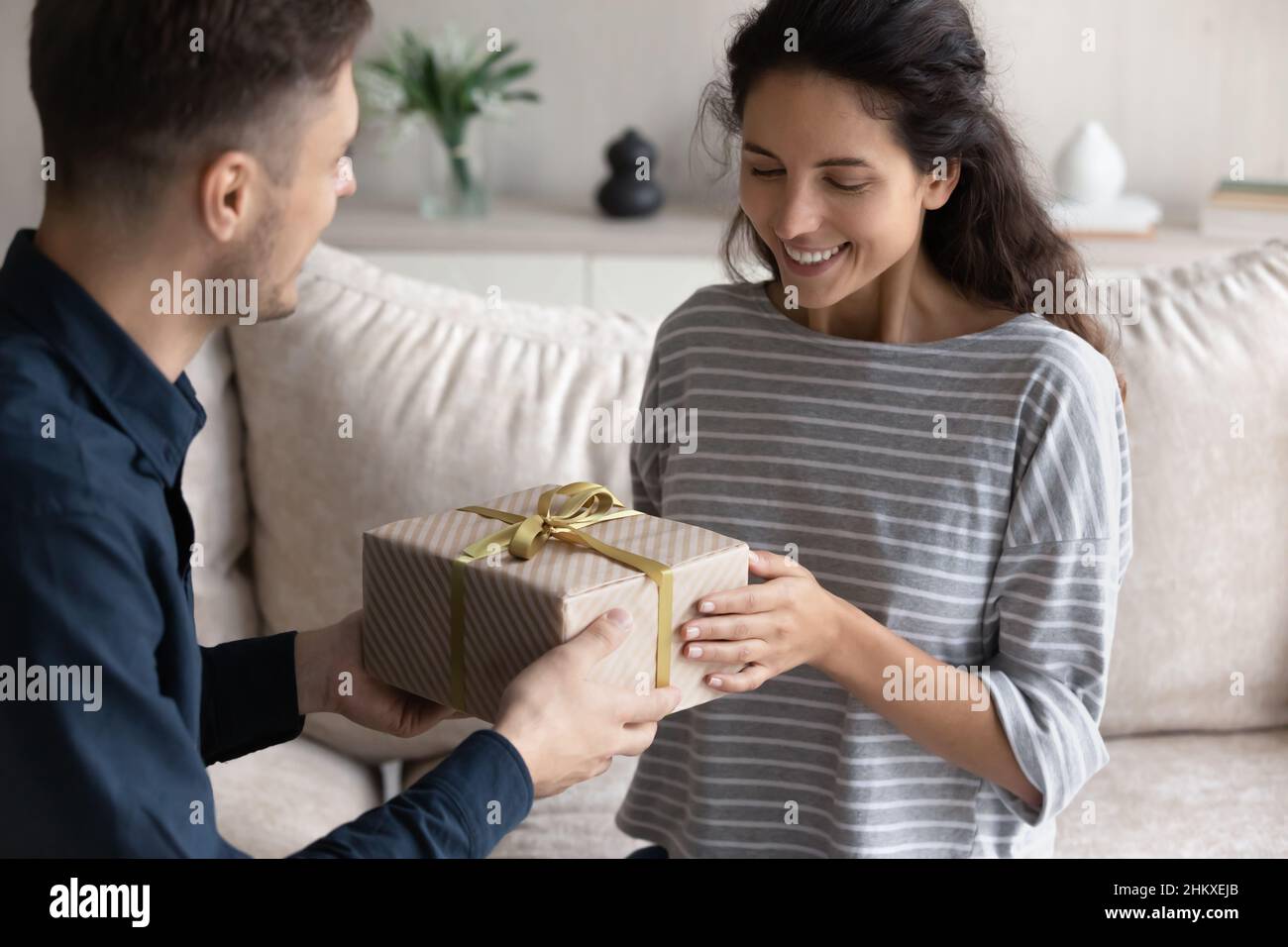 Petit ami aimant félicitant petite amie souriante, donnant boîte cadeau Banque D'Images