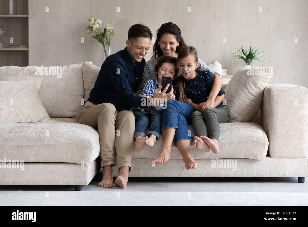 Parents et enfants heureux s'amuser avec un smartphone à la maison Banque D'Images