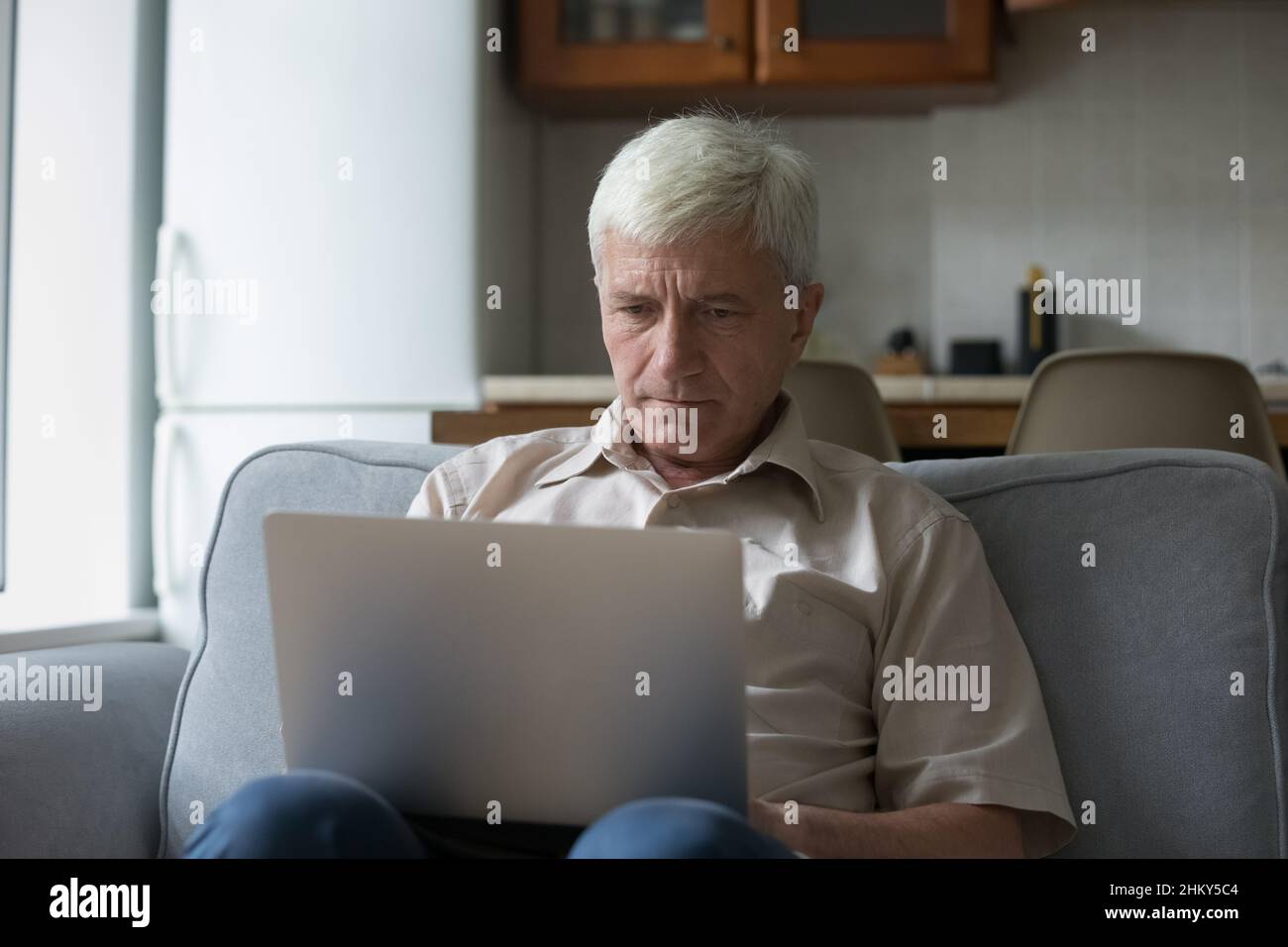 Utilisateur d'ordinateur mûr et concentré, homme reposant sur la table de traitement Banque D'Images