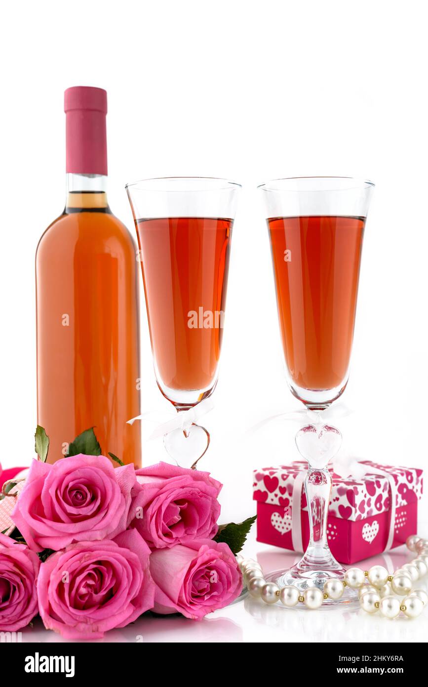 Concept de la Saint-Valentin.Bouteille avec deux verres de vin, roses roses, boîte-cadeau et corde de perles sur fond blanc avec espace pour le texte.Se Banque D'Images