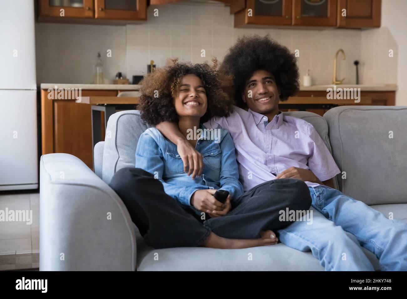 Joyeux couple africain de l'adolescence regardant la télévision, film de comédie Banque D'Images