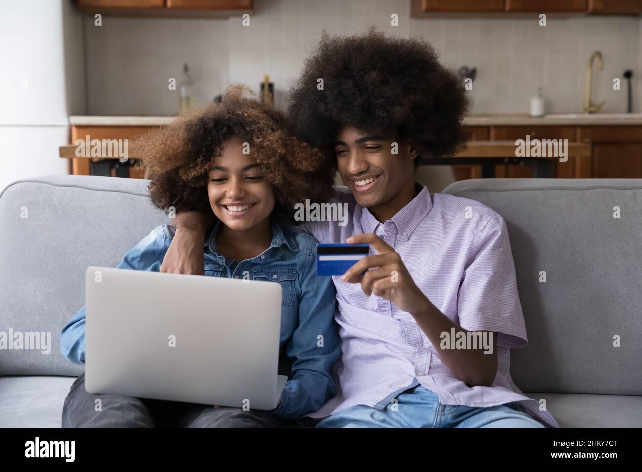 Joyeux couple d'étudiants africains de la génération Z qui s'embrasse sur un canapé Banque D'Images