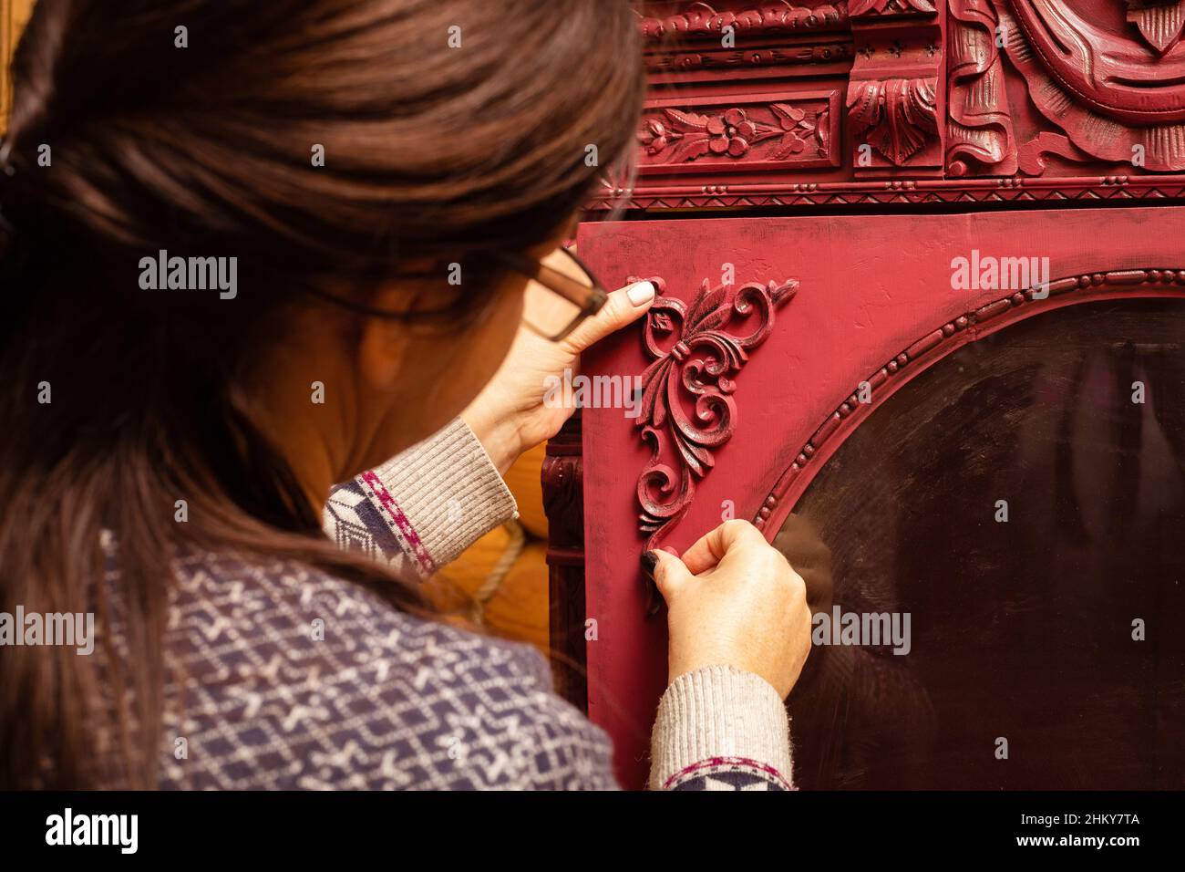 Femme d'âge moyen portant des lunettes encollage de nouvelles belles décorations en bois sculptées au carton rouge dans l'atelier pour la restauration de meubles.Écologique.Réutiliser Banque D'Images