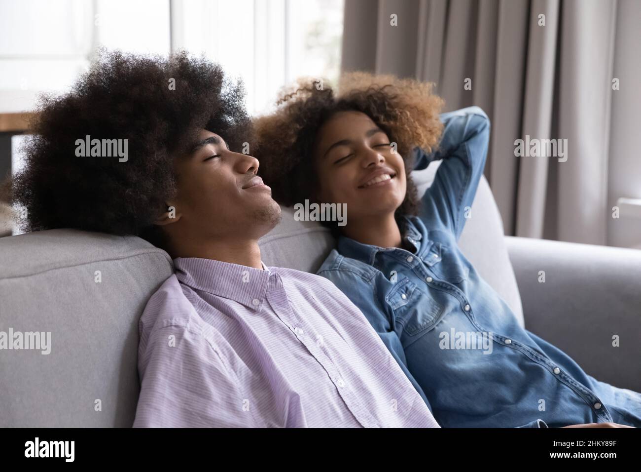 Un couple heureux d'adolescents indépendants noirs se détendant sur un canapé Banque D'Images