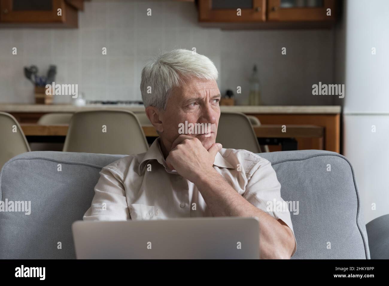 Pensive contrainte mature 70s homme tenant ordinateur portable Banque D'Images