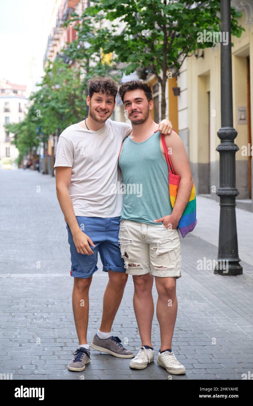 Un couple gay souriant se serre et regarde la caméra dans la rue. Banque D'Images