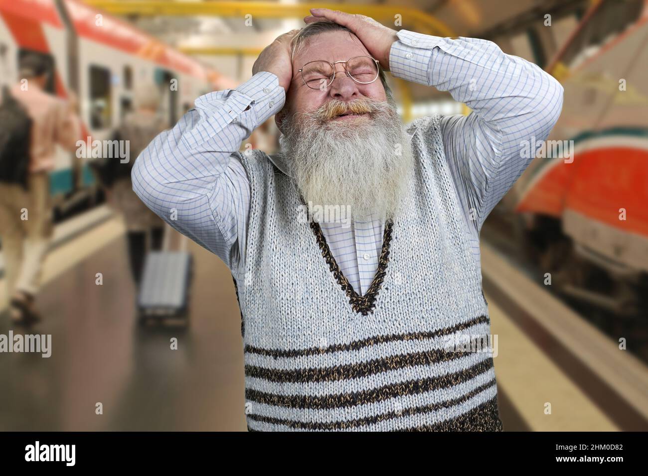 Vieux barbu homme portant un pull décontracté sensation de stress et de désespoir.Gare de Blur en arrière-plan. Banque D'Images