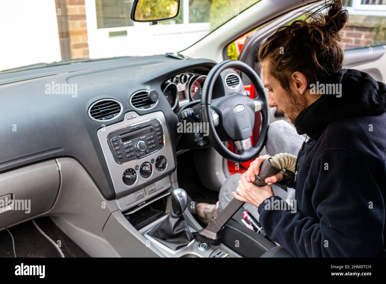 Woodbridge, Suffolk, Royaume-Uni février 24 2021: Un jeune homme adulte nettoyant sa voiture.Nettoyer les poubelles et aspirer la saleté et la poussière Banque D'Images