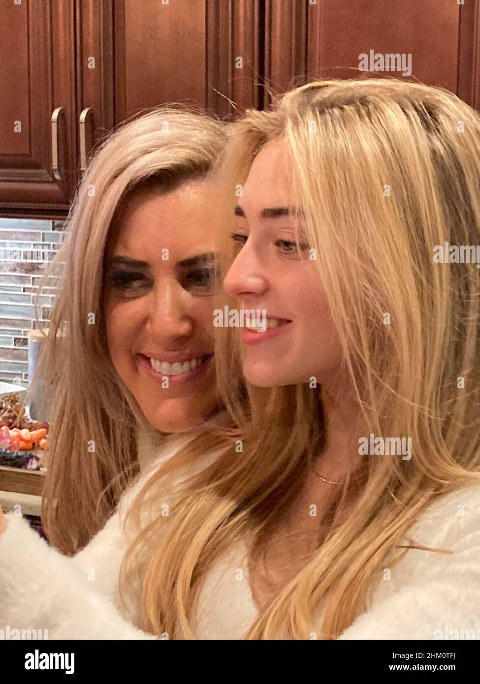 Mère et fille de l'adolescence appréciant certains ensemble temps.Des sourires éclatants mettent en lumière leurs cheveux presque assortis. Banque D'Images
