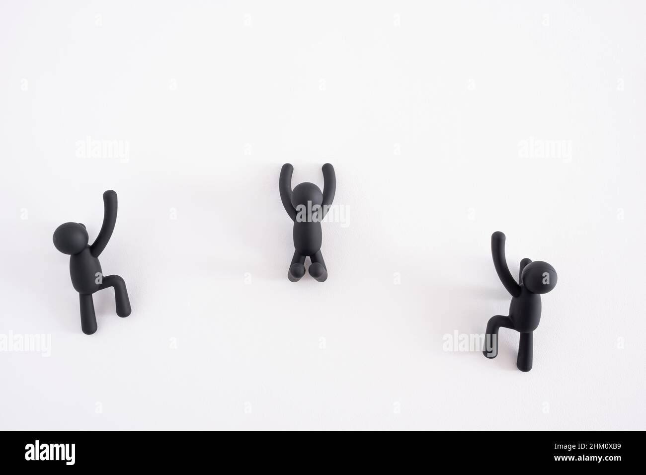 Trois marionnettes noires de 3D grimpant sur un fond blanc, 3D personnes, personnage humain, personne accrochée à un mur blanc, concept d'amélioration de soi Banque D'Images