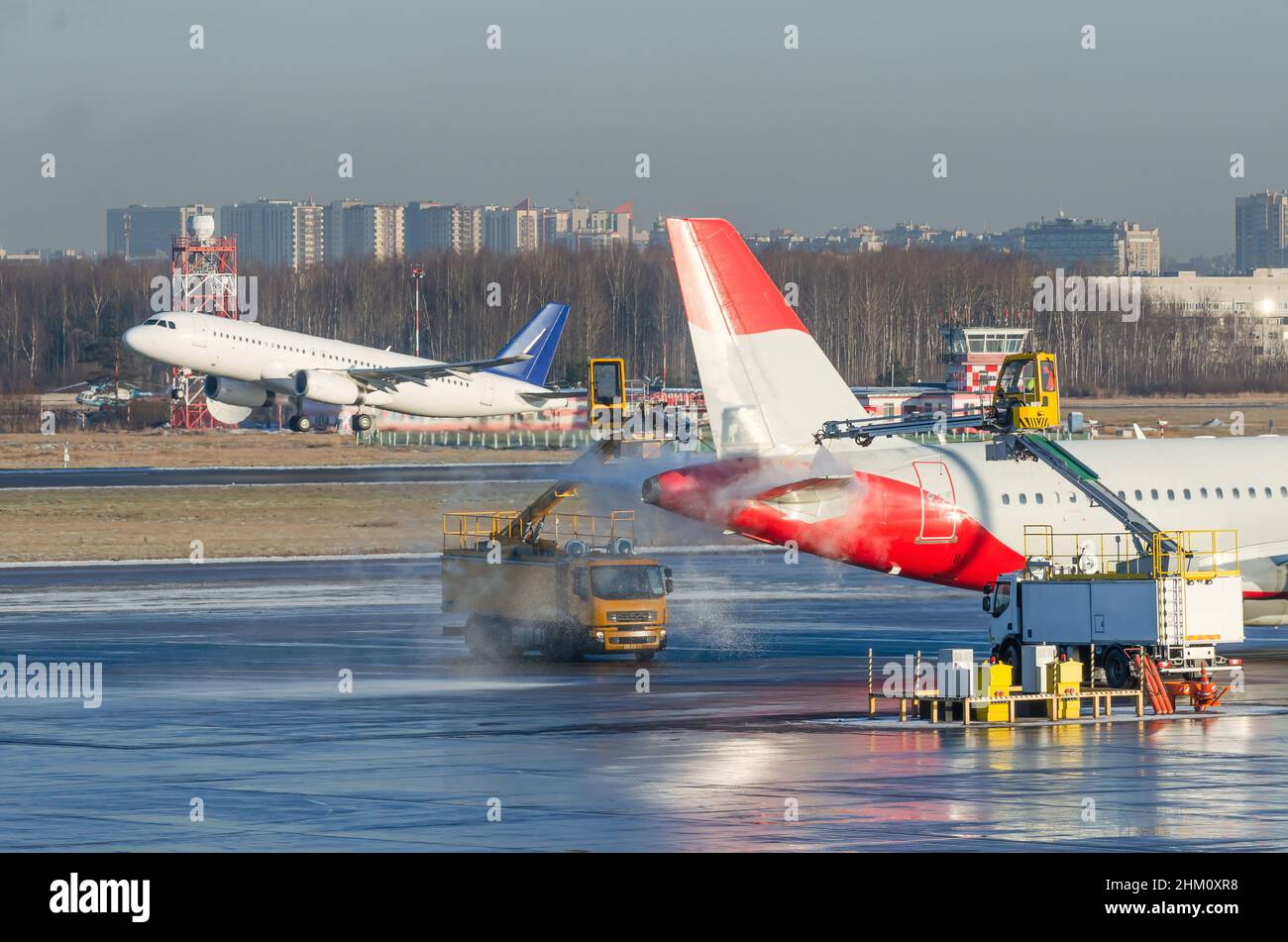 Dégivrage de l'aile de l'avion avant le vol.Hiver givré jour à l'aéroport, et un avion de décollage en arrière-plan Banque D'Images
