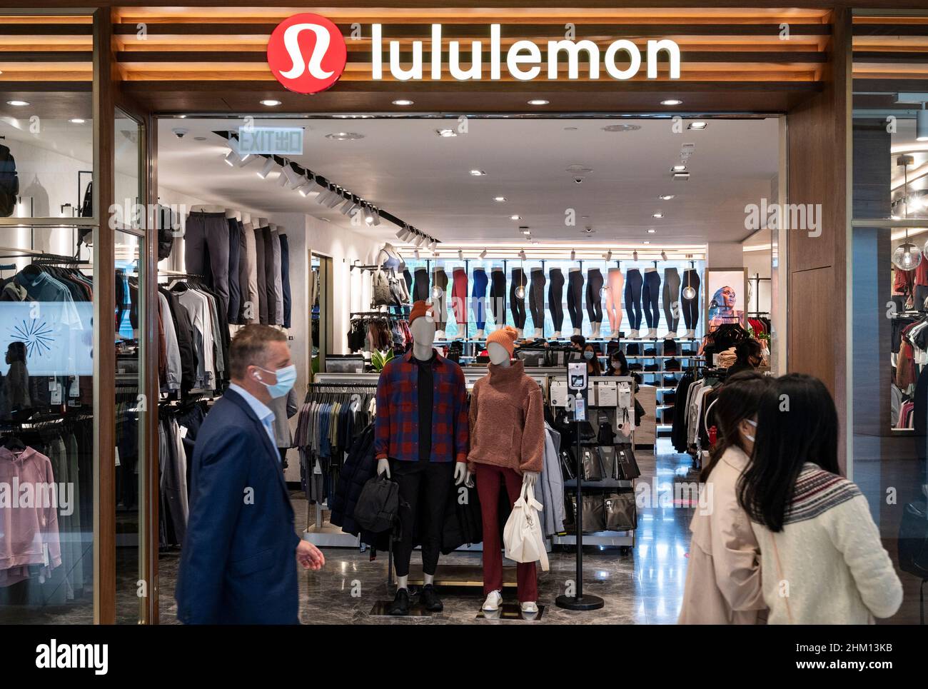 Les acheteurs marchent devant le groupe de vêtements de sport canadien, le magasin Lululemon à Hong Kong. Banque D'Images