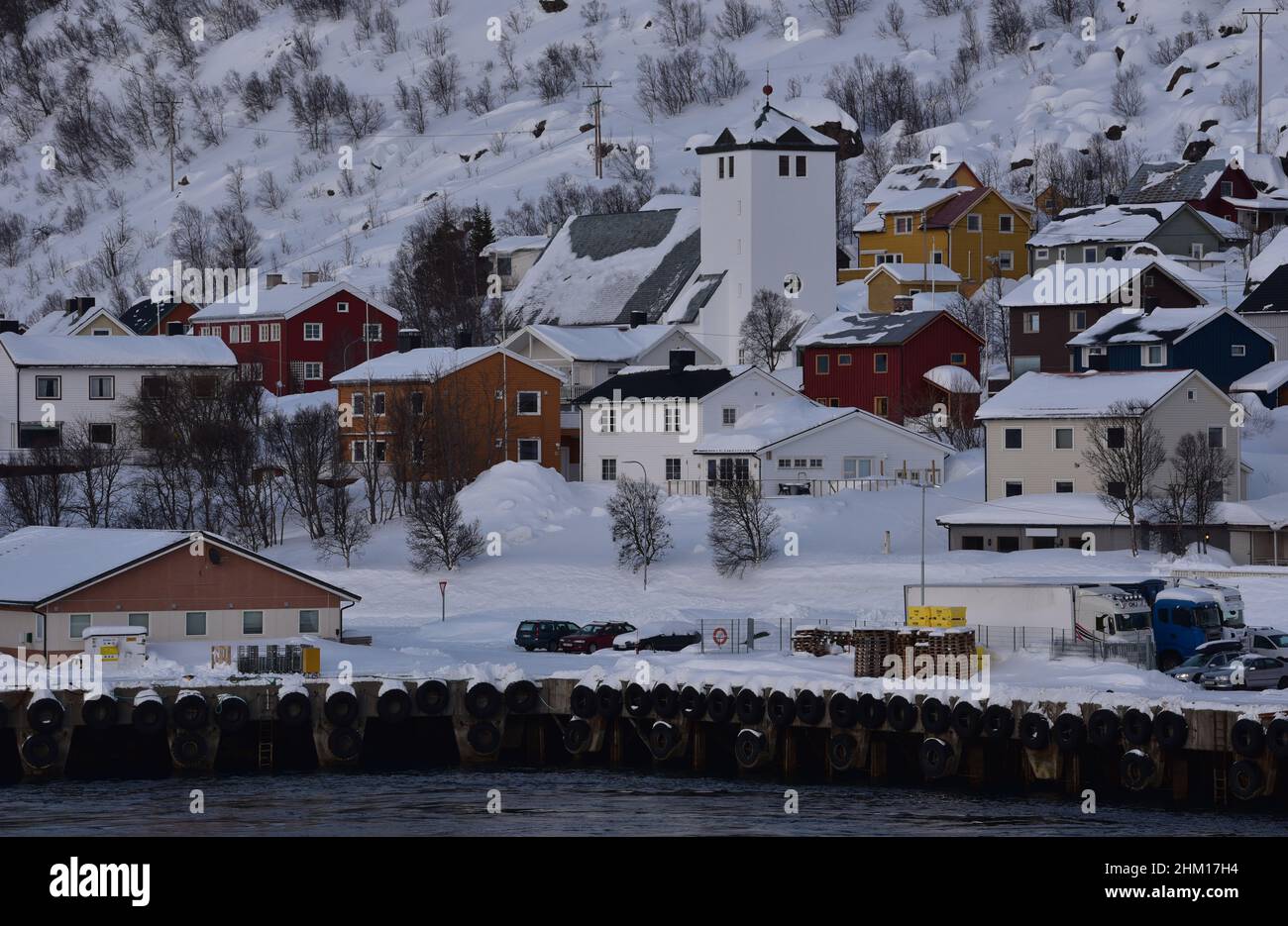 L'église Øksfjord et les maisons norvégiennes peintes perchées sur une colline enneigée dans le petit village de pêcheurs d'Øksfjord, Norvège, Europe. Banque D'Images