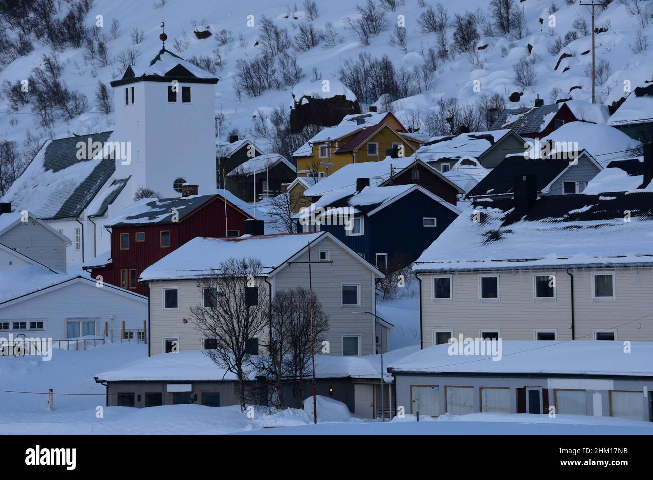 L'église Øksfjord et les maisons norvégiennes peintes perchées sur une colline enneigée dans le petit village de pêcheurs d'Øksfjord, Norvège, Europe. Banque D'Images