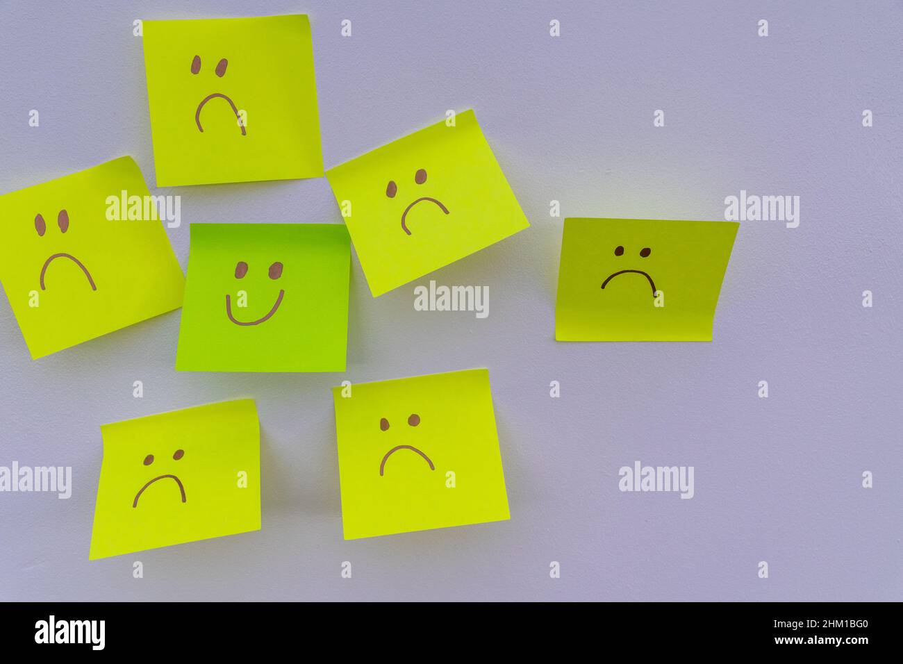 Un visage souriant heureux parmi de nombreux visages tristes.Cacher la dépression, les problèmes de santé mentale ou le concept d'anxiété.Arrière-plan des concepts de deux faces.Faire semblant fa Banque D'Images