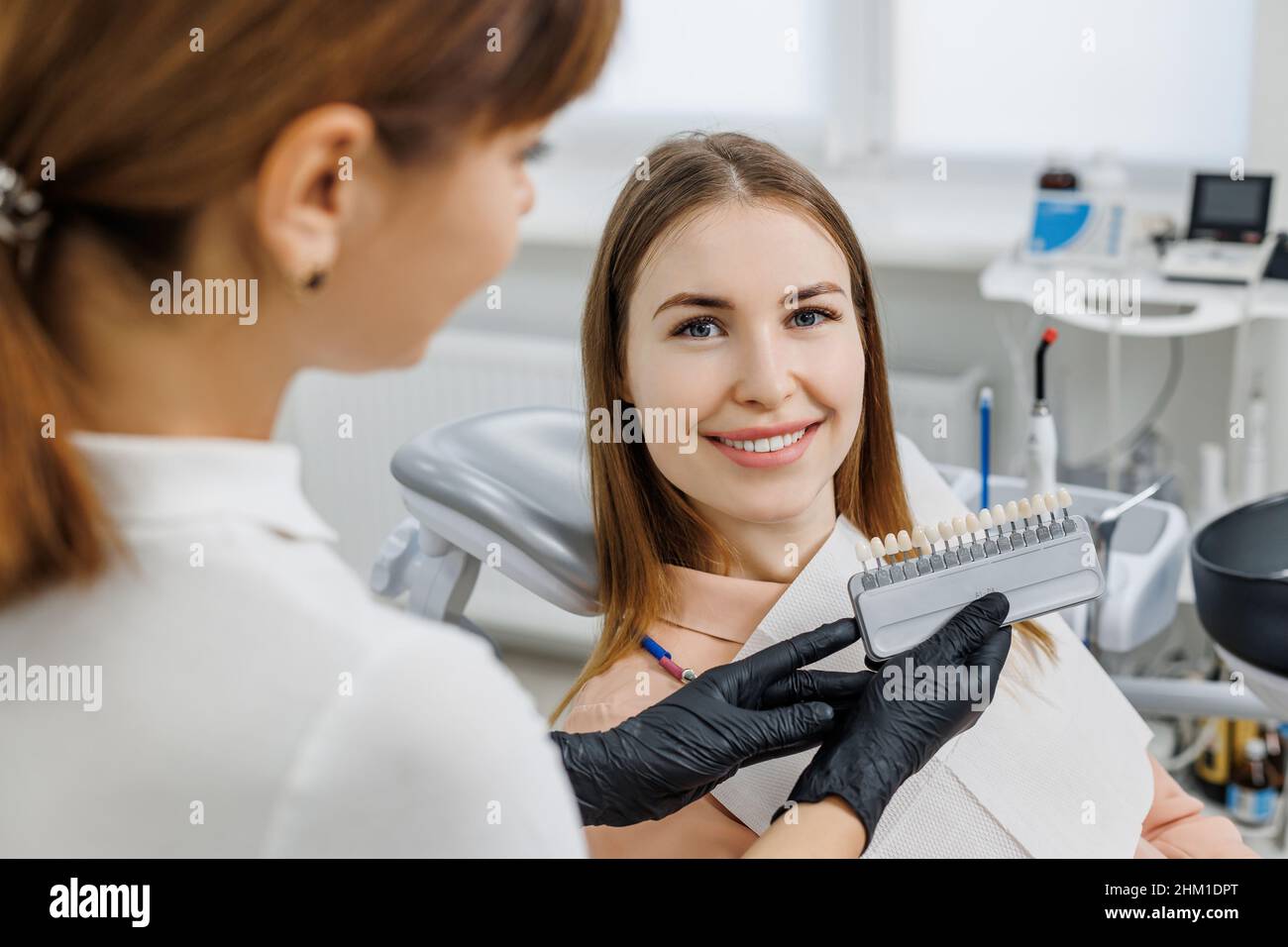 Le dentiste démontrera pour le patient les nuances de couleur des dents guide pour le blanchiment des dents.Échantillons de couleur des dents correspondant aux implants ou aux facettes dans les mains du médecin.Photo de concept sur le thème dentaire. Banque D'Images