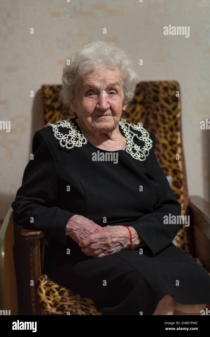 Un portrait d'une vieille femme assise dans un fauteuil. Banque D'Images