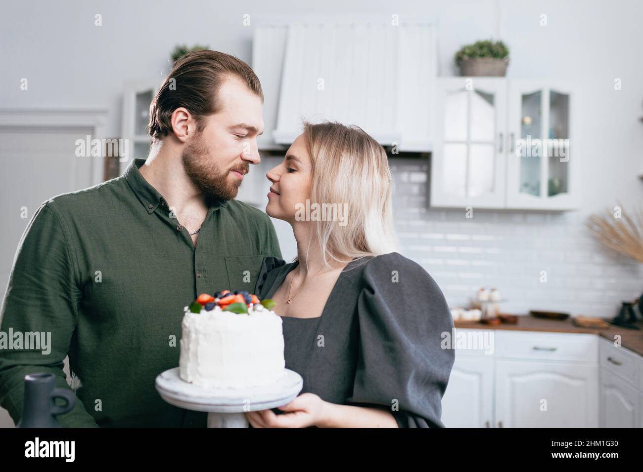 Pâtisserie chef confiserie jeune femme caucasienne avec mari amour petit ami homme essayez le goût du gâteau sur la cuisine maison table. Gâteaux petits gâteaux et dessert sucré Banque D'Images