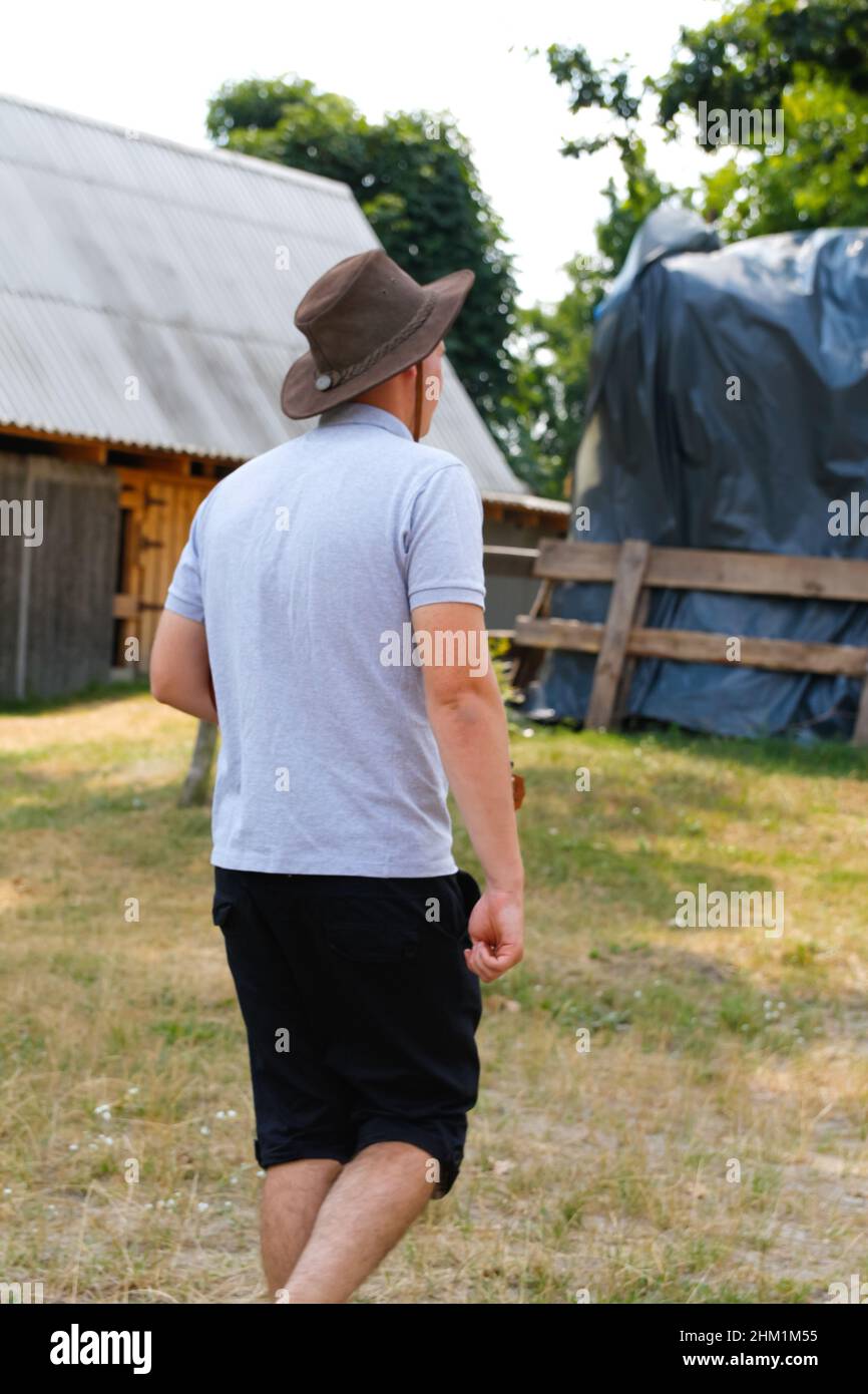 Homme en chapeau.Portrait d'un fermier souriant avec de l'herbe verte et de la nature des arbres en arrière-plan.Jeune homme portant un chapeau de cow-boy sur le terrain.Gros plan.Joyeux jeune p Banque D'Images