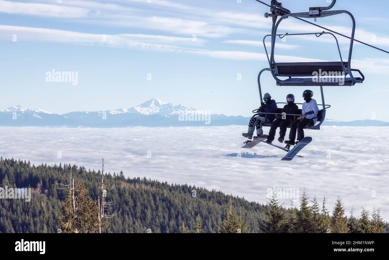 Personnes sur un télésiège à la station de ski de Grouse Mountain avec mnt Baker en arrière-plan Banque D'Images