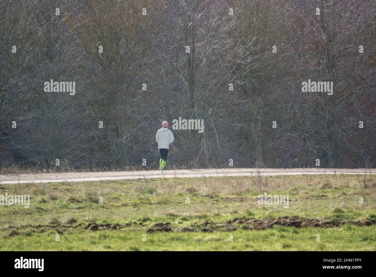 homme portant des chaussettes haute visibilité qui jogging sur une piste non faite Banque D'Images