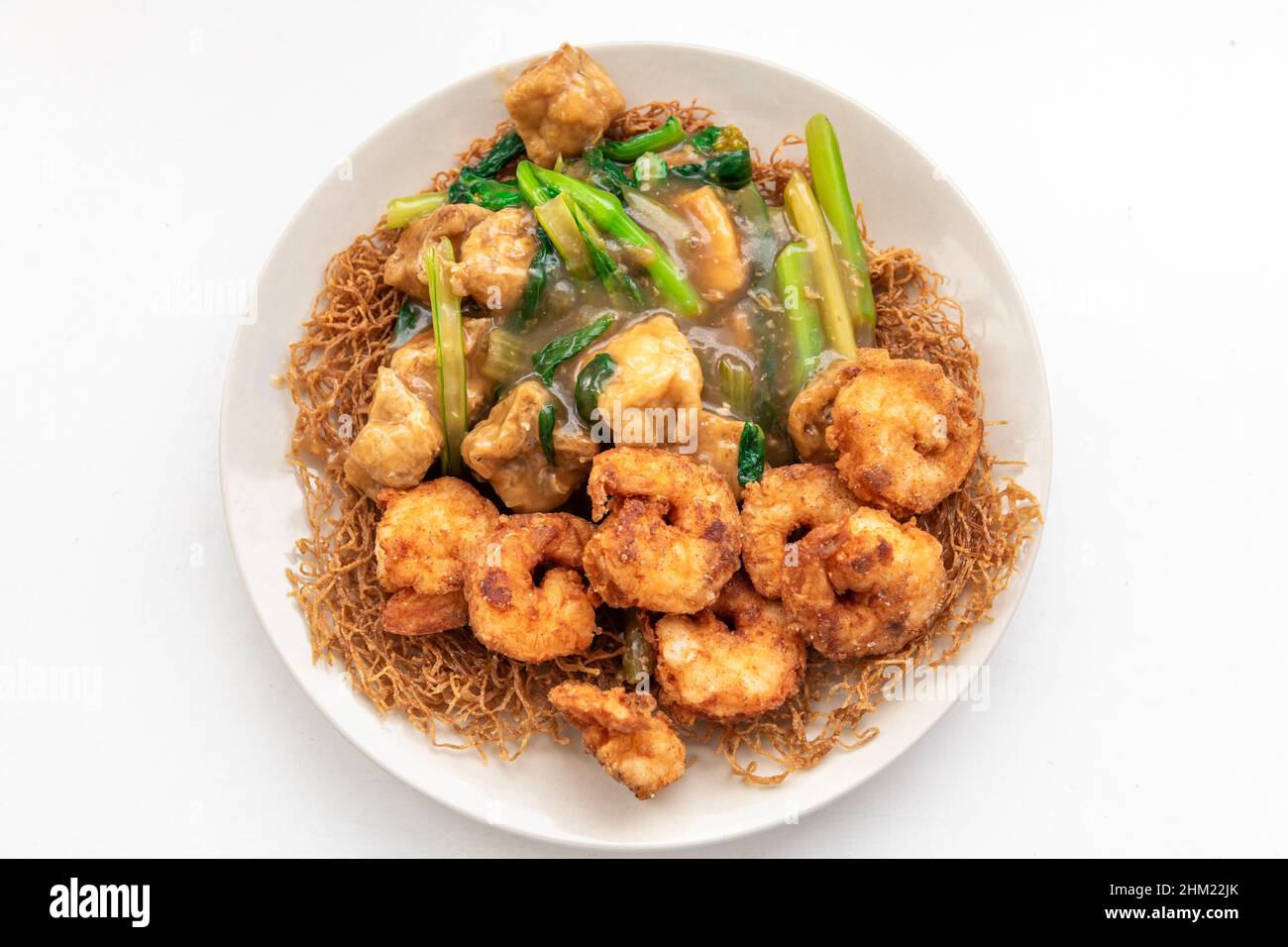 Assiette de nouilles grillées croustillantes avec tofu frit, crevettes royales et légumes verts de saison. Banque D'Images